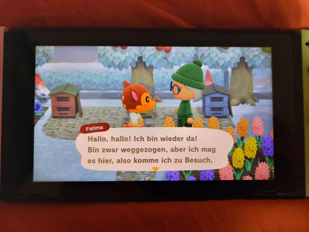 Der Bildschirm einer Switch mit meiner Spielfigur und einer weiteren Figur namens Fatima. Fatima sagt gerade "Hallo, hallo! Ich bin wieder da! Bin zwar weggezogen, aber ich mag es hier, also komme ich zu Besuch."