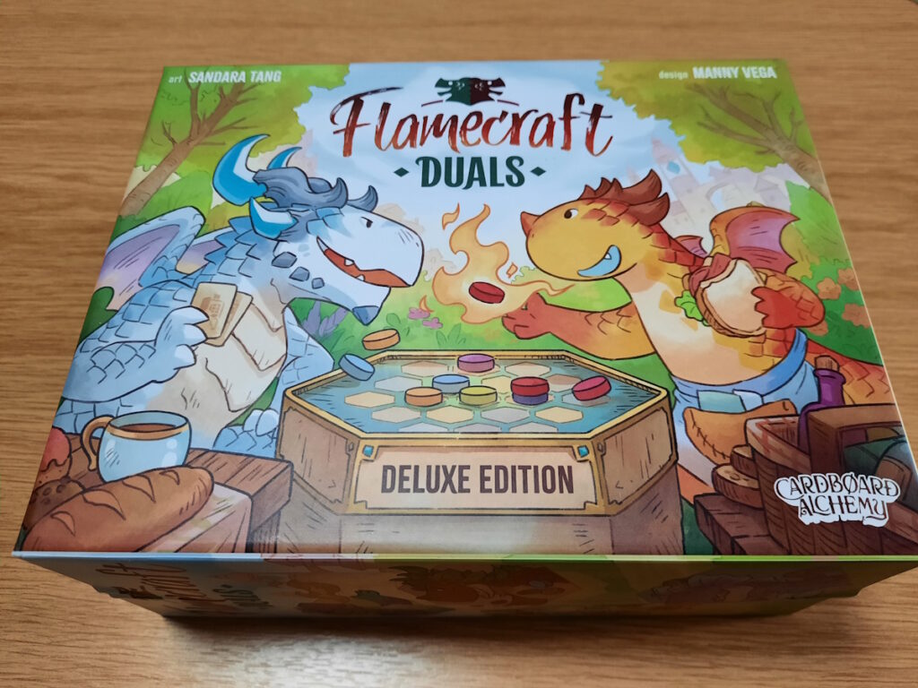 Die Schachtel des Spiels "Flamecraft Duals". Das Cover zeigt zwei Drachen, die einander an einem sechseckigen Spielbrett gegenüber sitzen.
