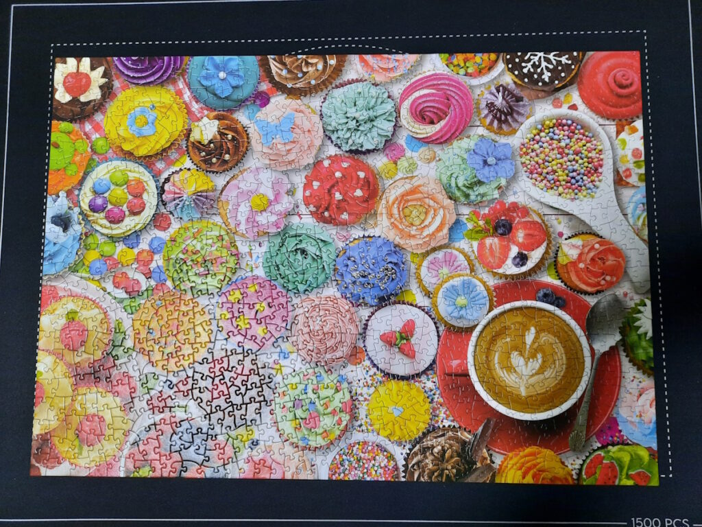 Ein fertiges Puzzle, dessen Motiv lauter bunt dekorierte Cupcakes auf einem Tisch zeigt.