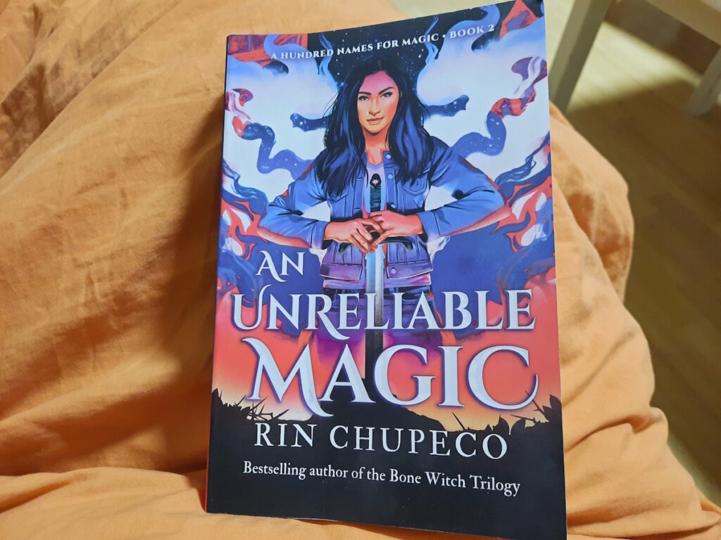 Die Taschenbuchausgabe von "An Unreliable Magic" von Rin Chupeco.