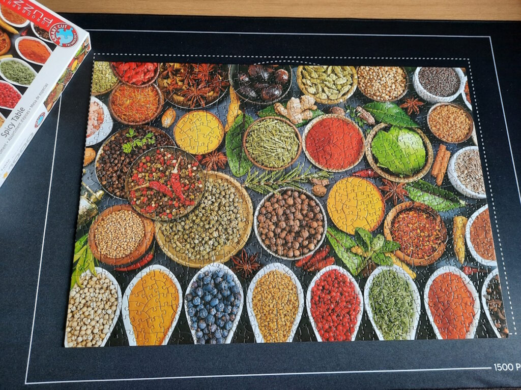 Ein fertiges Puzzle, dessen Motiv lauter Schalen mit verschiedenen farbenfrohen Gewürzen zeigt.