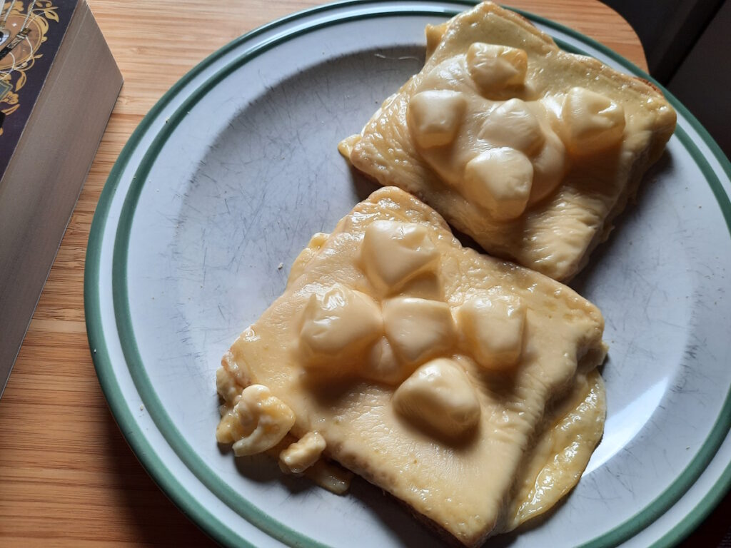 Zwei Hawaii-Toast auf einem Teller. Der Käse ist schön geschmolzen und darunter sind jeweils fünf etwas dickere Ananasstücke zu erahnen.