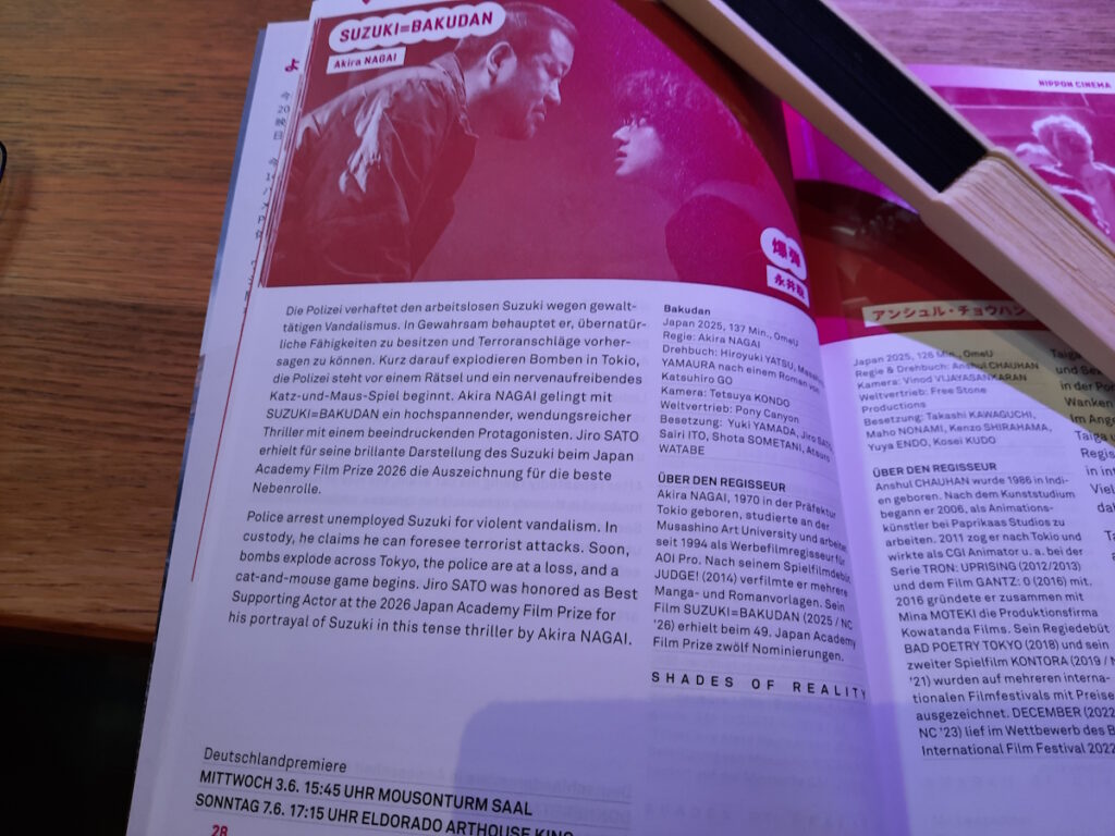 Der Programm-Eintrag der Nippon Connection zu dem Film Suzuki=Bakudan. Das dazugehörige Bild zeigt zwei Personen, die sich aggressiv anschauen.