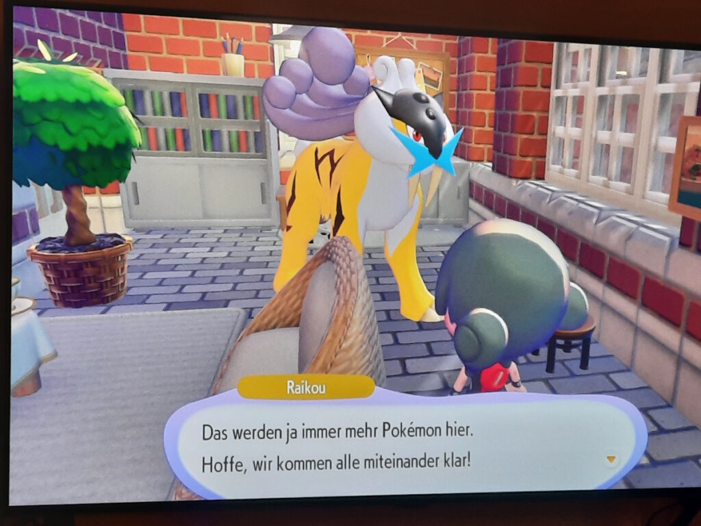 Raikou in seinem neuen Zuhause. Es ist ein Pokémon in einem roten Ziegelsteingebäude zu sehen, das an eine große gelbe Raubkatze erinnert.